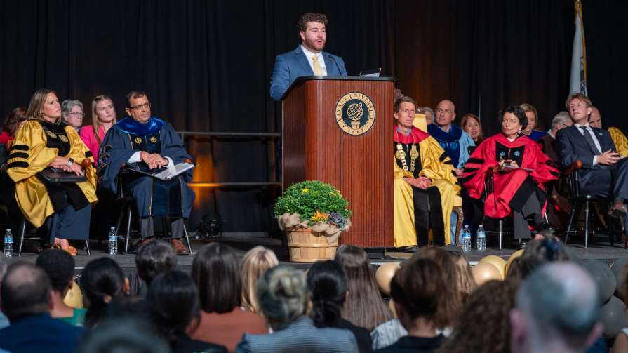 Brian Inger speaks to students from podium at Bryant's Convocation.